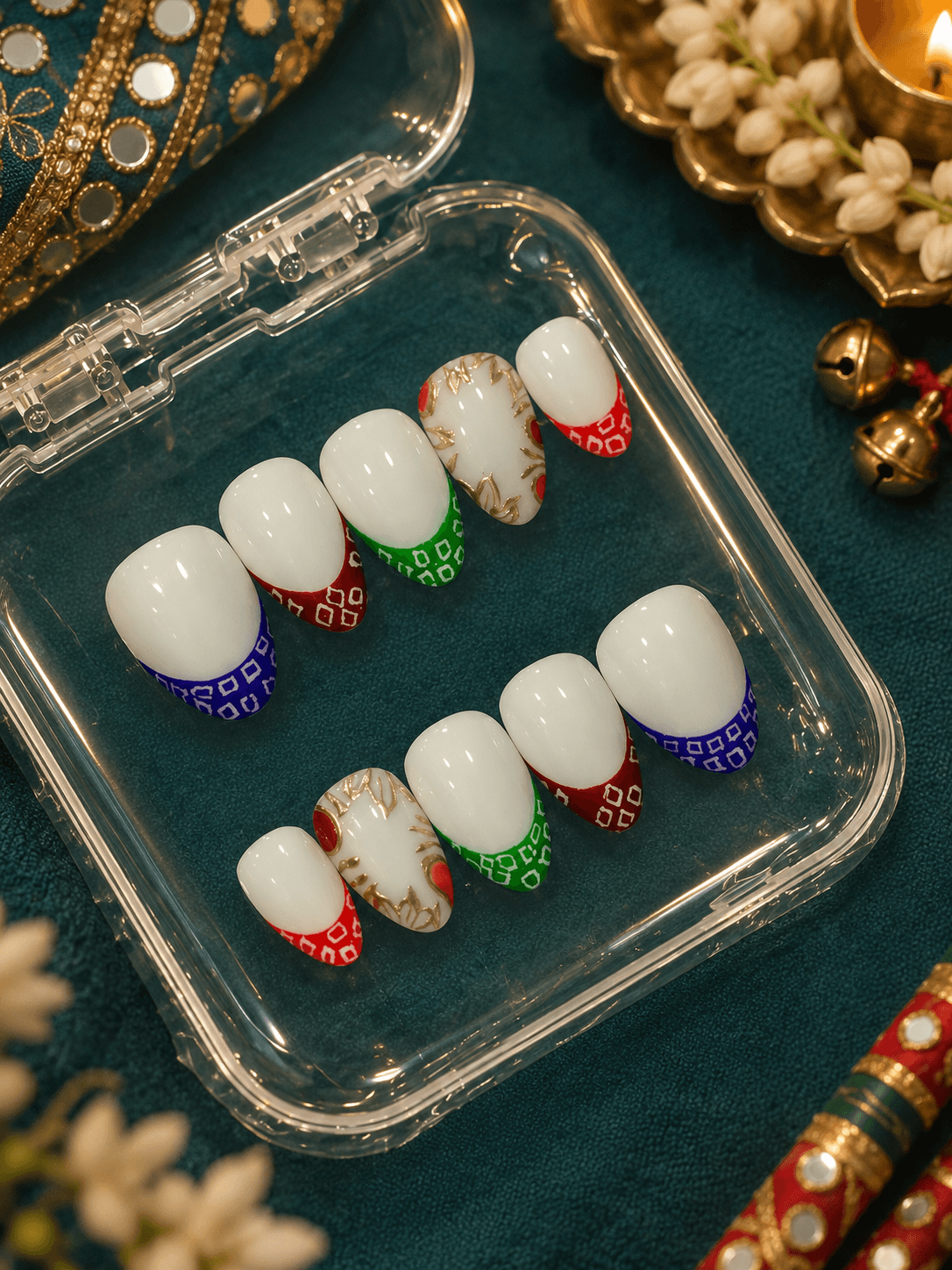 Bandhani tips & Gold accents — Glossy white nails with colorful bandhani-print tips in red, green, and blue, and a hand-painted floral accent.