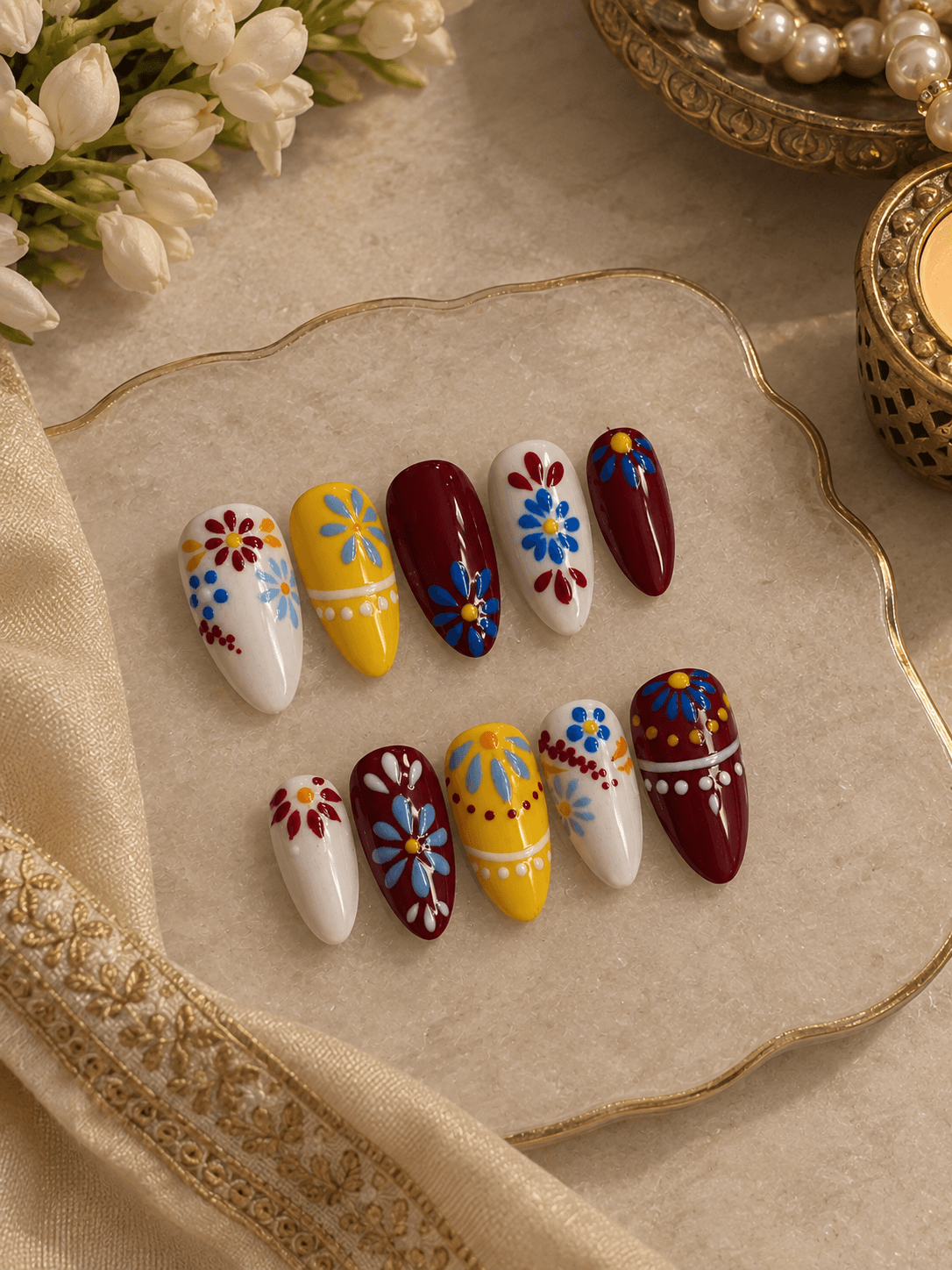 Phulkari Bloom — Almond nails in white, mustard, and maroon with hand-painted folk flowers in bold colors.